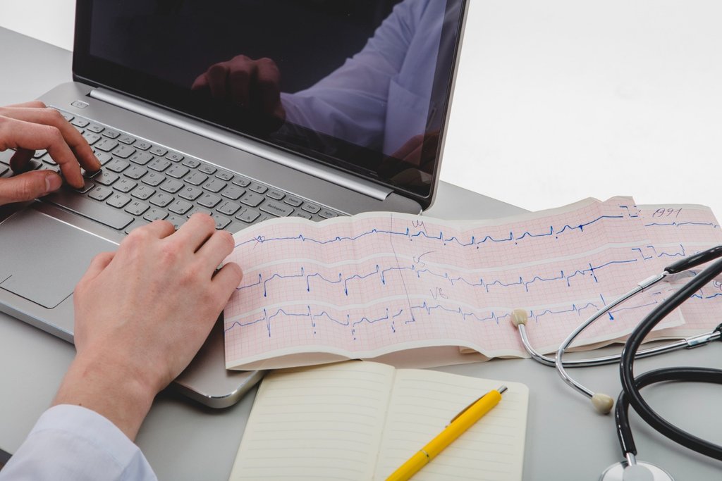 Výsledok EKG pacienta vedľa počítaču na stole.