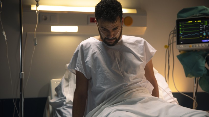 Mladý človek po operácií na nemocničnom lôžku s prístrojmi