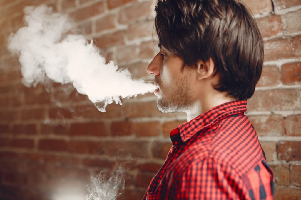 Mladi muz vyfukujuci cigaretovy dym