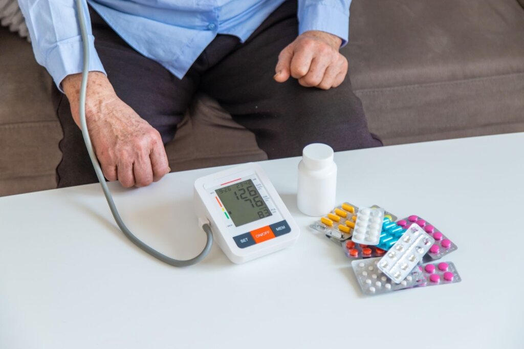 Senior si merá krvný tlak pomocou tlakomeru.